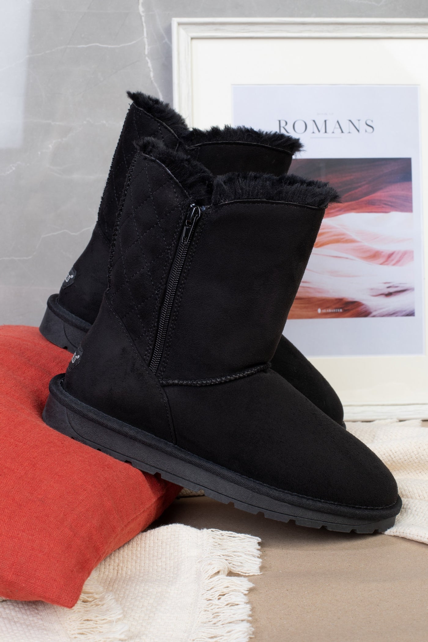 Paire de bottines fourrées Abuela noires sur un coussin rouge, vue de trois-quarts