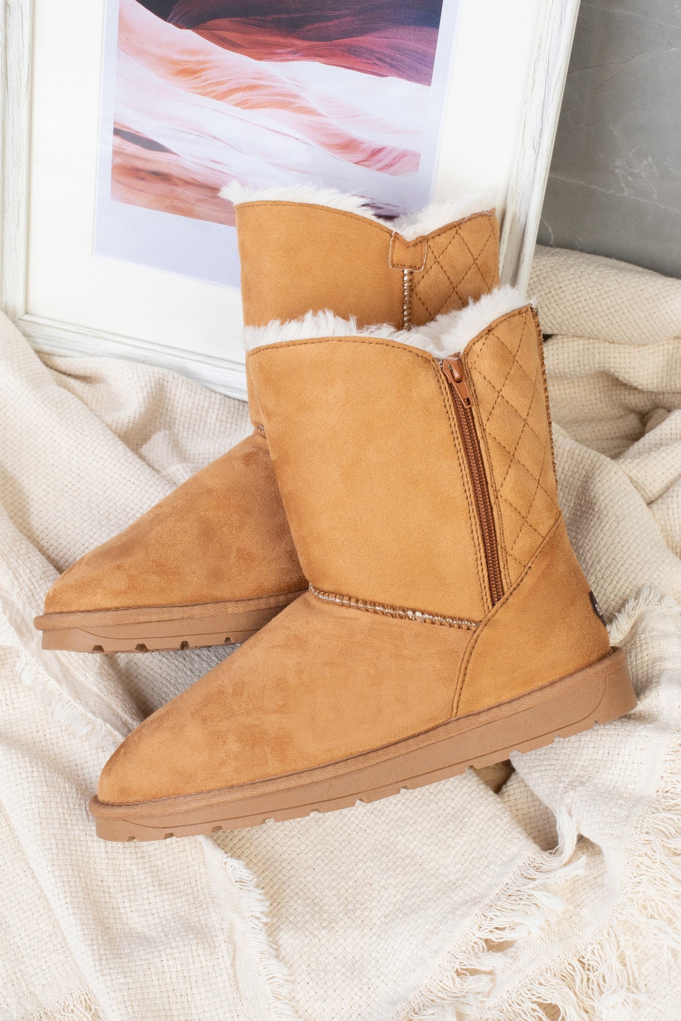 Bottines fourrées Abuela camel posées sur un plaid crème frangé, vue de trois-quarts
