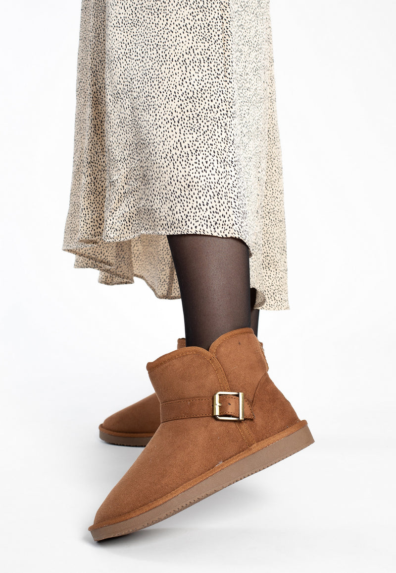 Bottines fourrées Charriton camel portées avec des collants noirs et une robe écrue