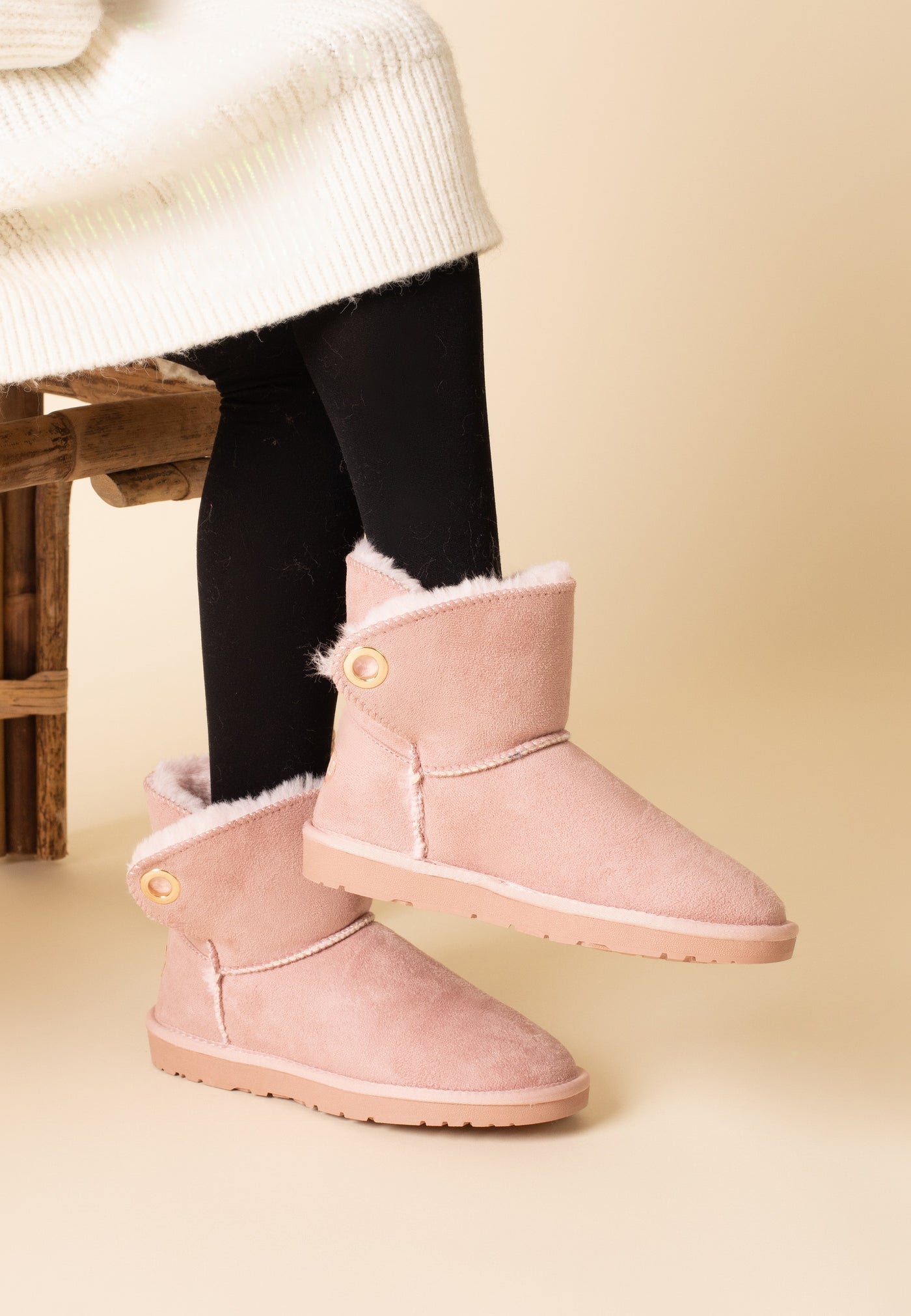 Bottines fourrées Ridley rose portées avec un collant sombre et un pull écru