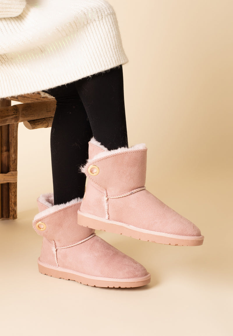 Bottines fourrées Ridley rose portées avec un collant sombre et un pull écru