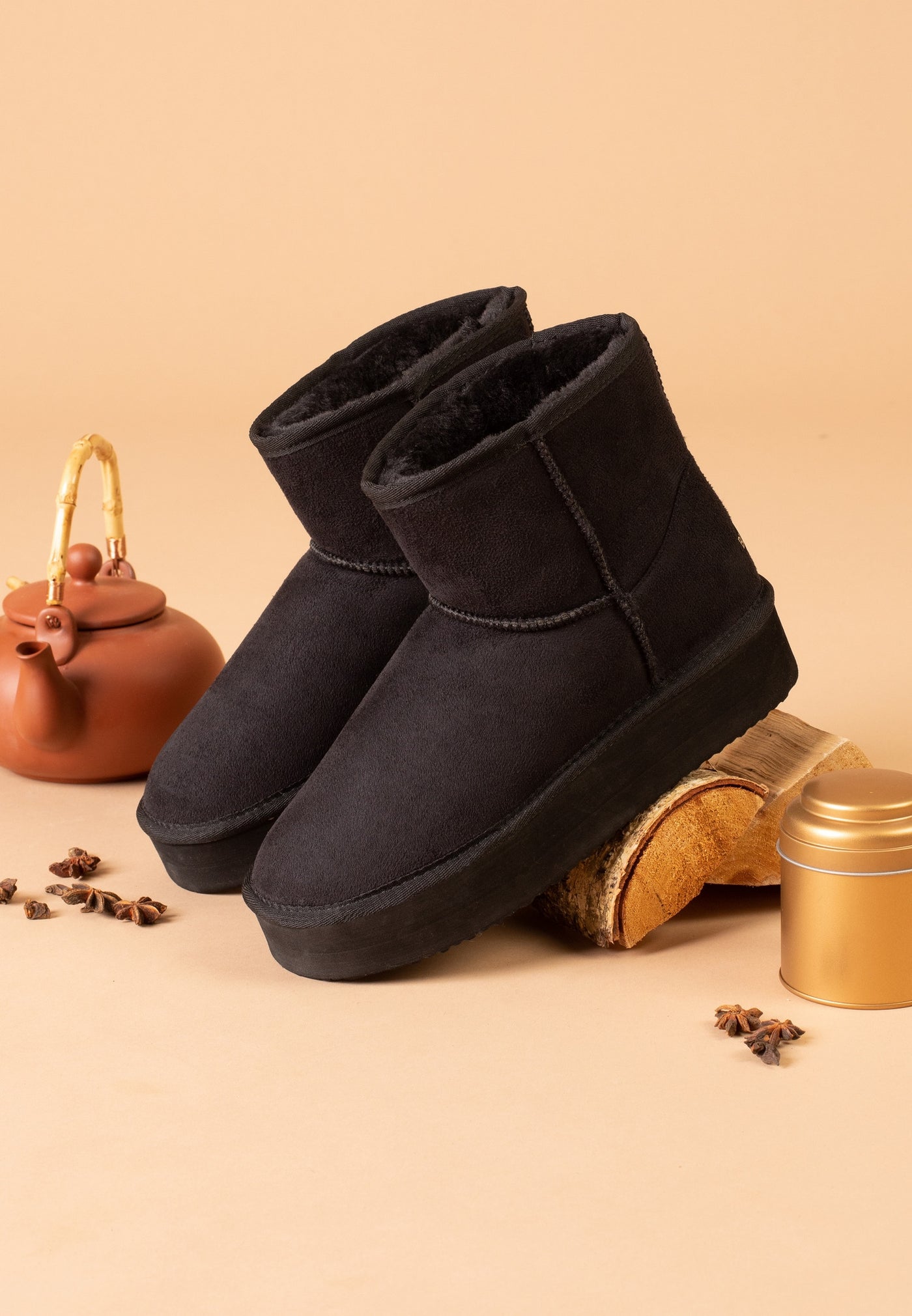 Paire de bottines fourrées Princesse noires de trois-quarts sur un fond abricot