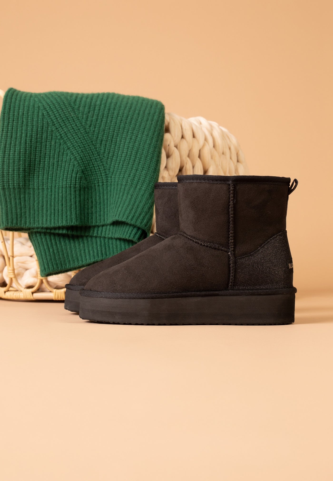 Paire de bottines fourrées Casablanca noires posée près d'un pull vert plié