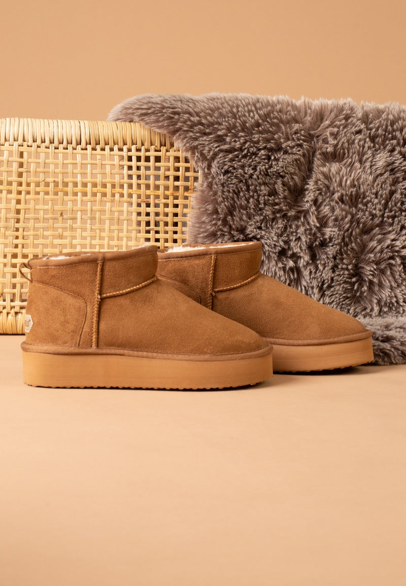 Bottines fourrées Milli camel posées de profil près d'un panier en cannage