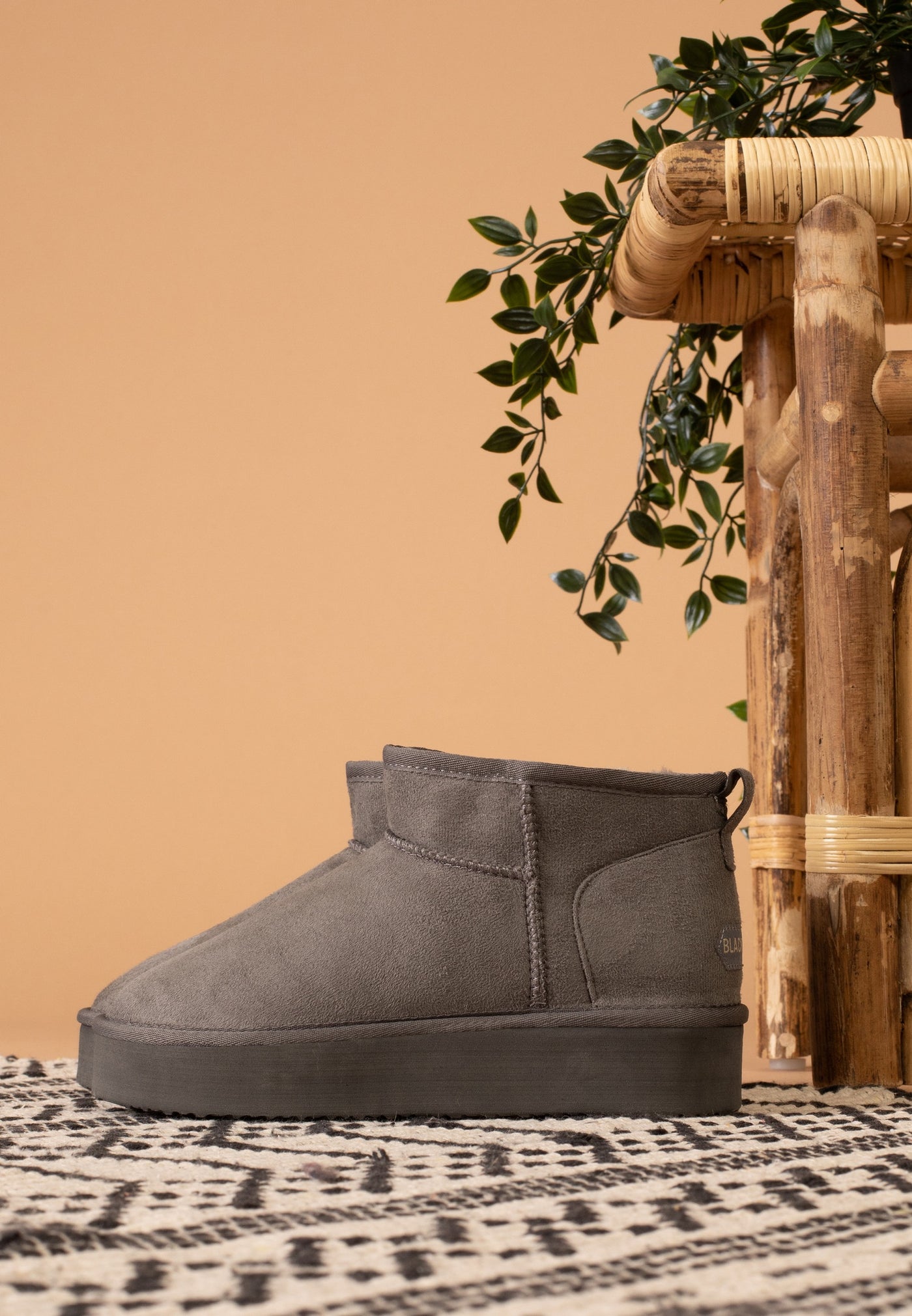 Bottine fourrée Milli anthracite de profil, posée sur un tapis à motifs noir et blanc