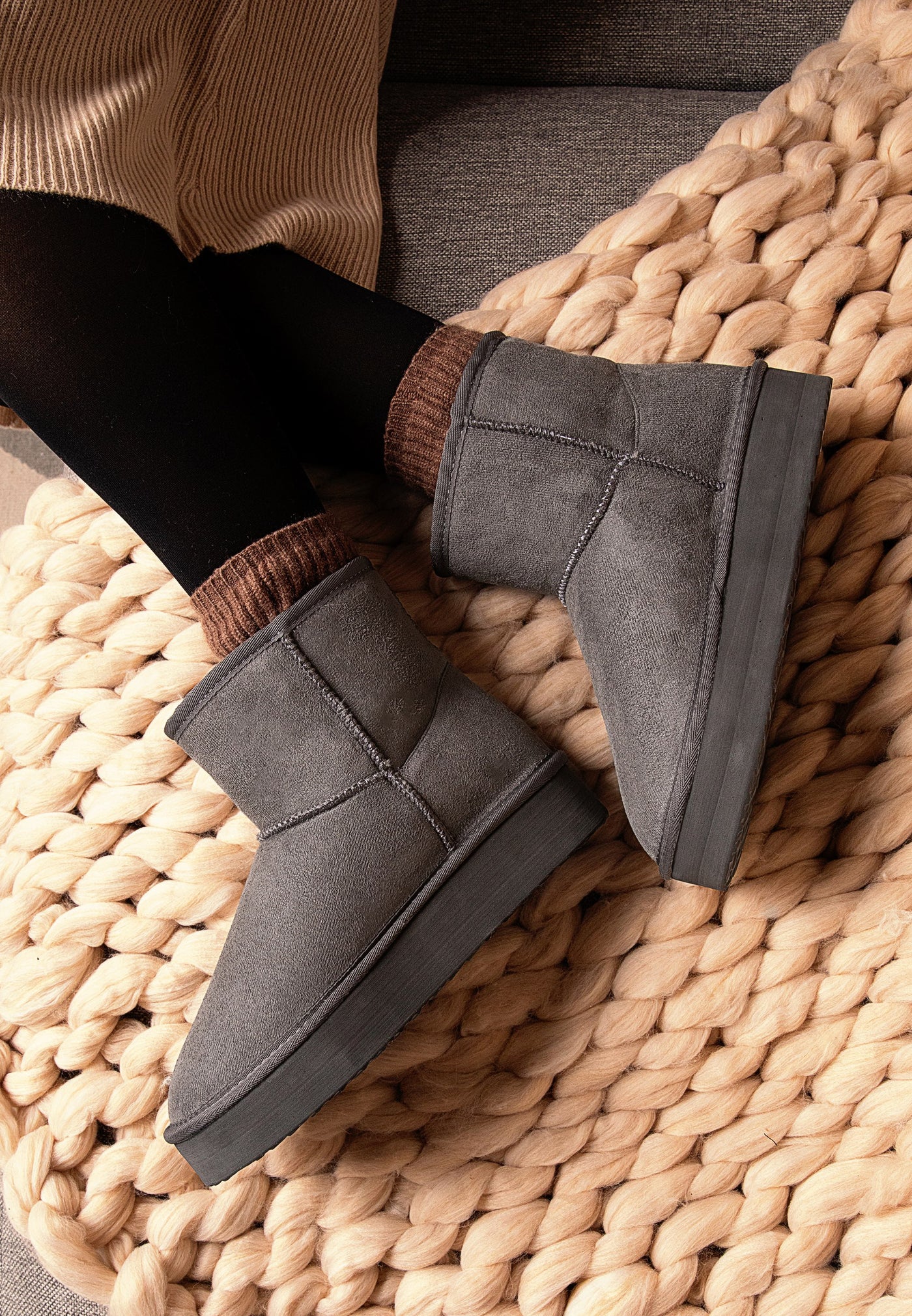 Bottines fourrées Princesse anthracite portées sur un plaid tressé, avec des collants noirs