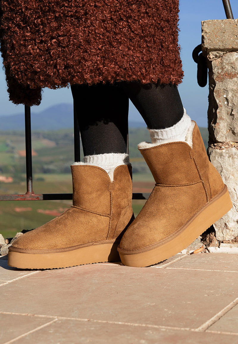 Bottines à plateforme fourrées Bellevue camel portées sur une terrasse, collants noirs et socquettes