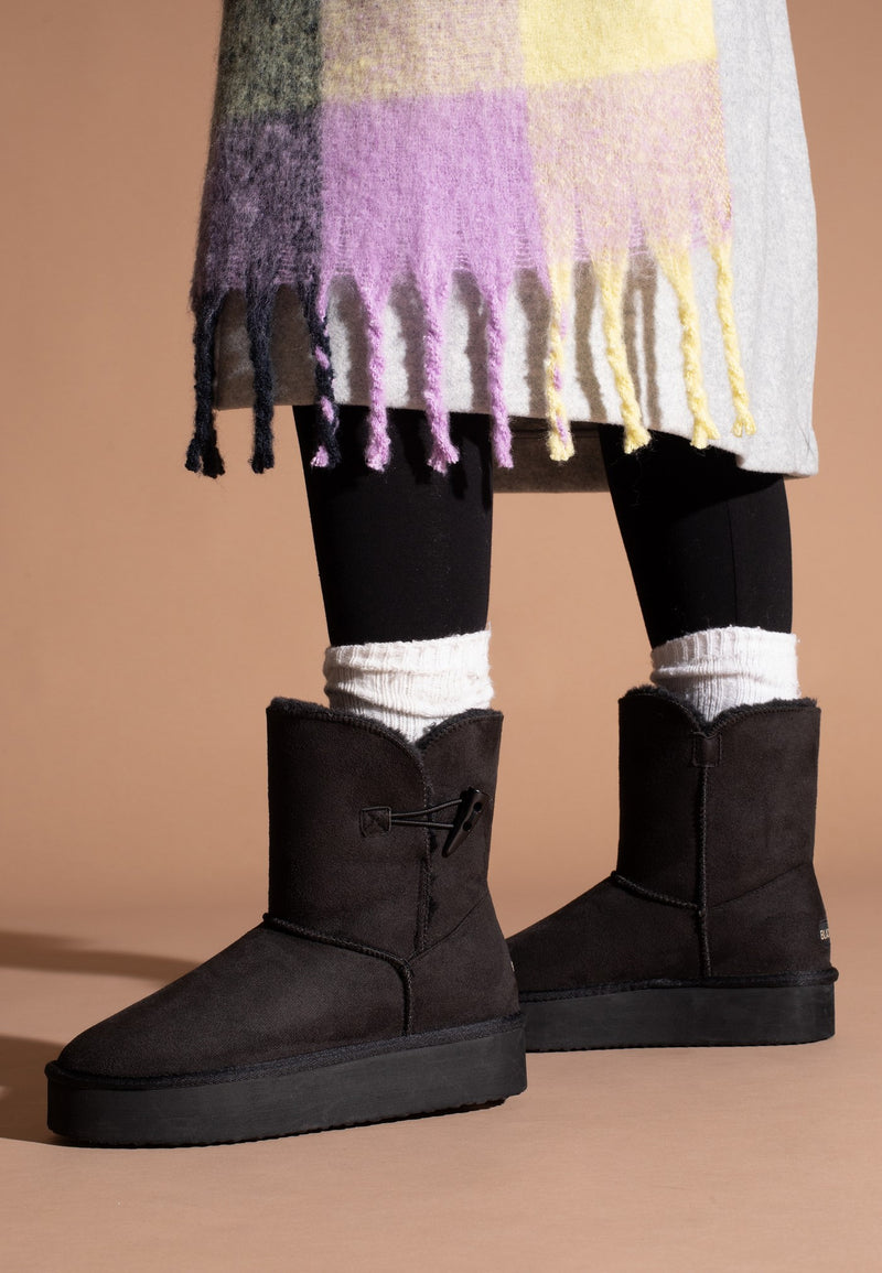 Deux bottines fourrées Anais noires portées avec une jupe grise et une écharpe