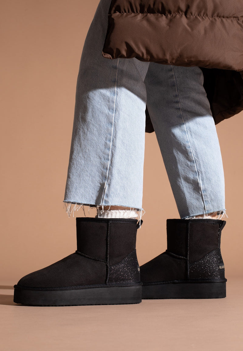 Bottines à plateforme fourrées Casablanca noires portées avec un jean clair, vue de trois-quarts