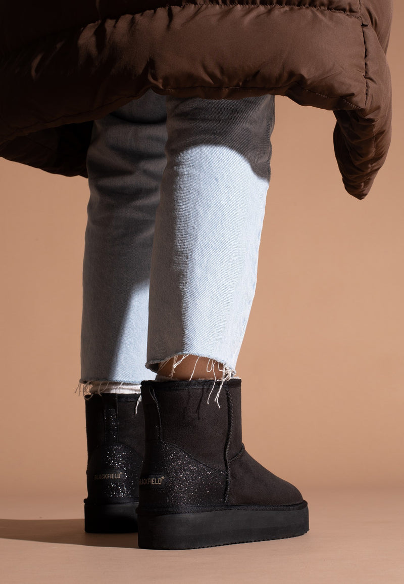 Bottines fourrées Casablanca noires portées de dos, logos dorés sur les contreforts