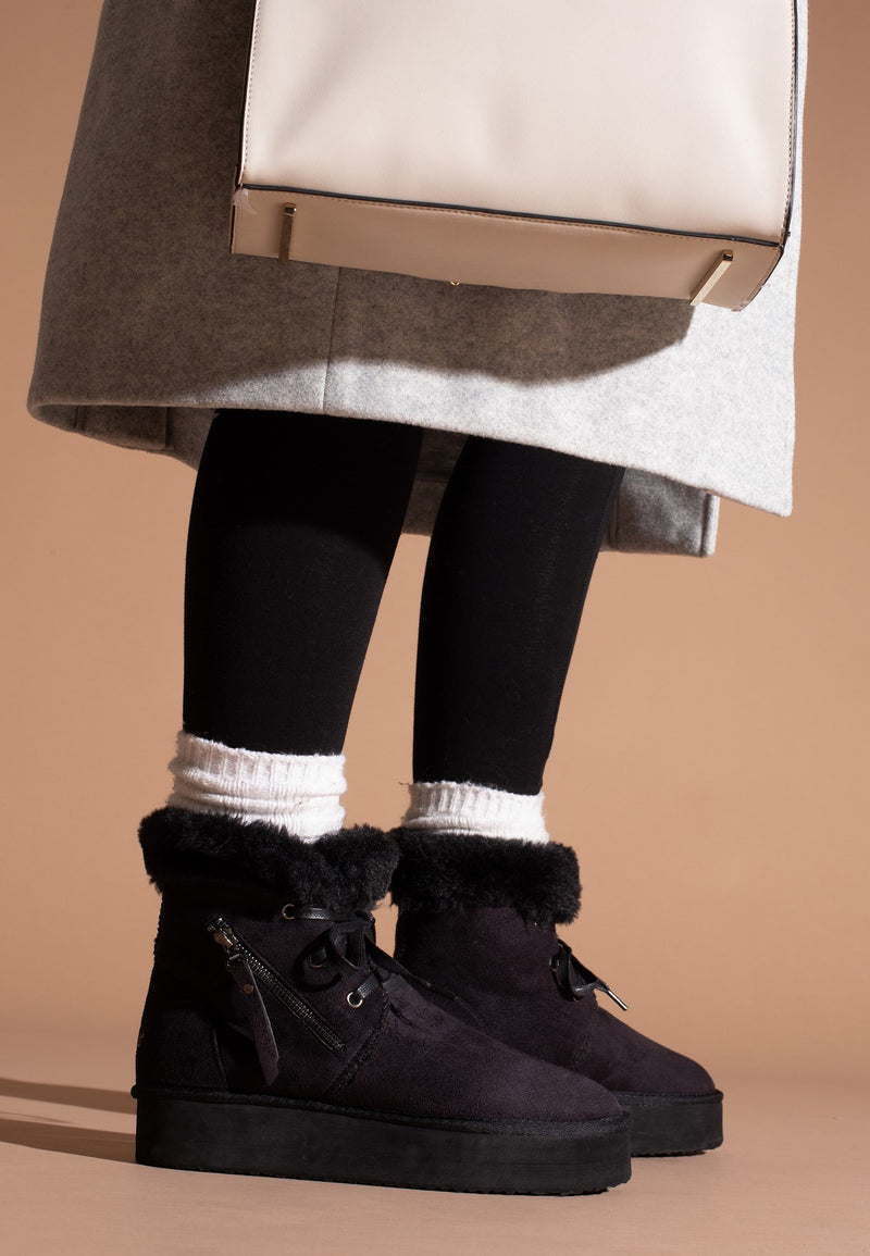 Bottines à plateforme fourrées Celia noires portées avec un collant noir et des socquettes