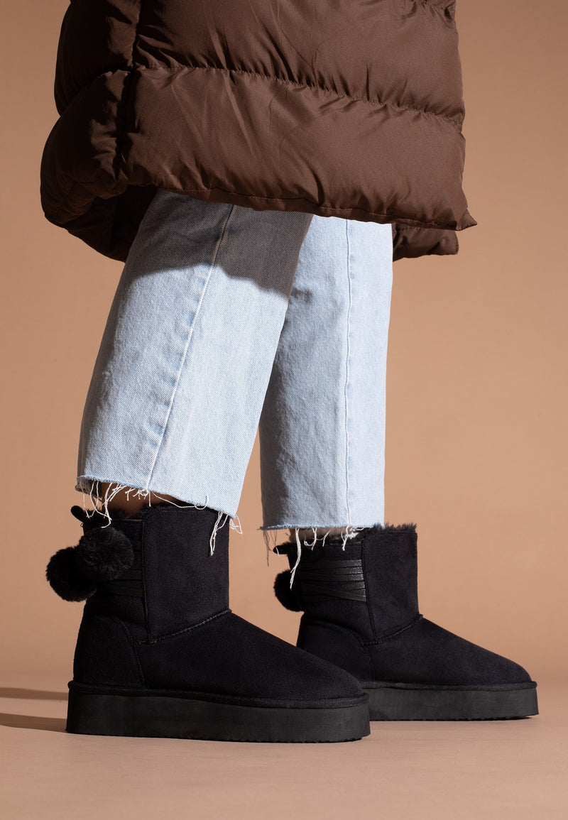 Bottines à plateforme fourrées Winnipeg noires portées avec un jean clair à ourlet frangé