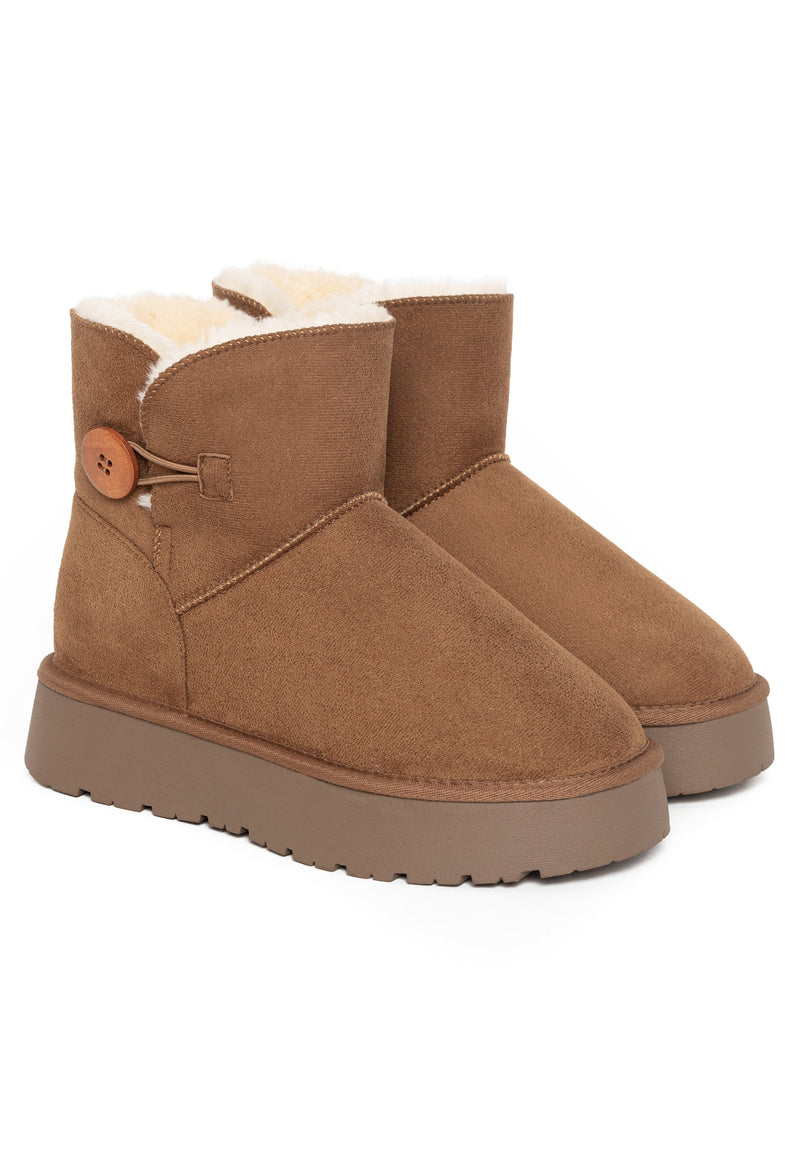 Deux bottines fourrées Clair camel posées de trois-quarts, bouton de bois au col