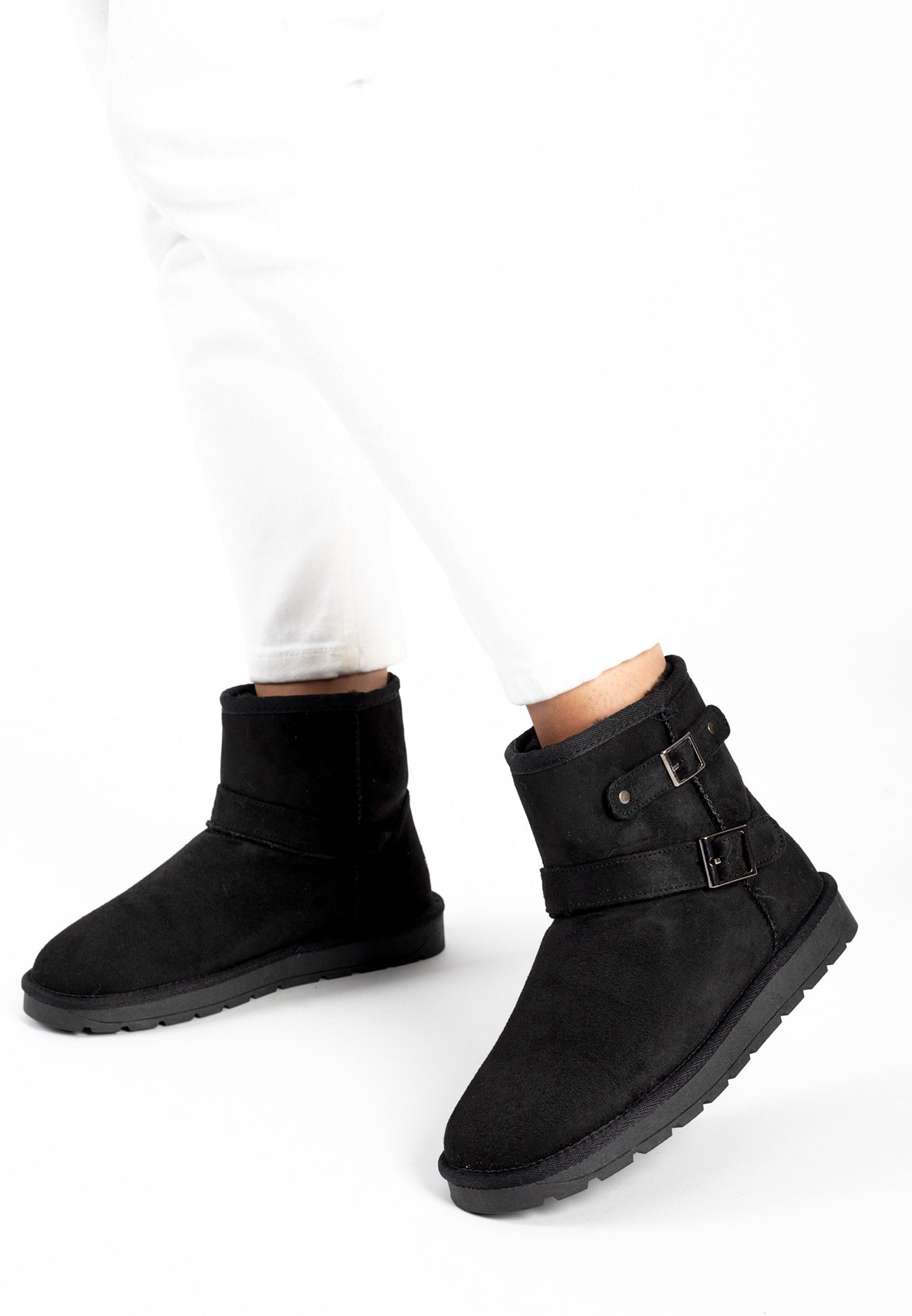 Bottines fourrées Olwen noires portées en marche sous un pantalon blanc droit
