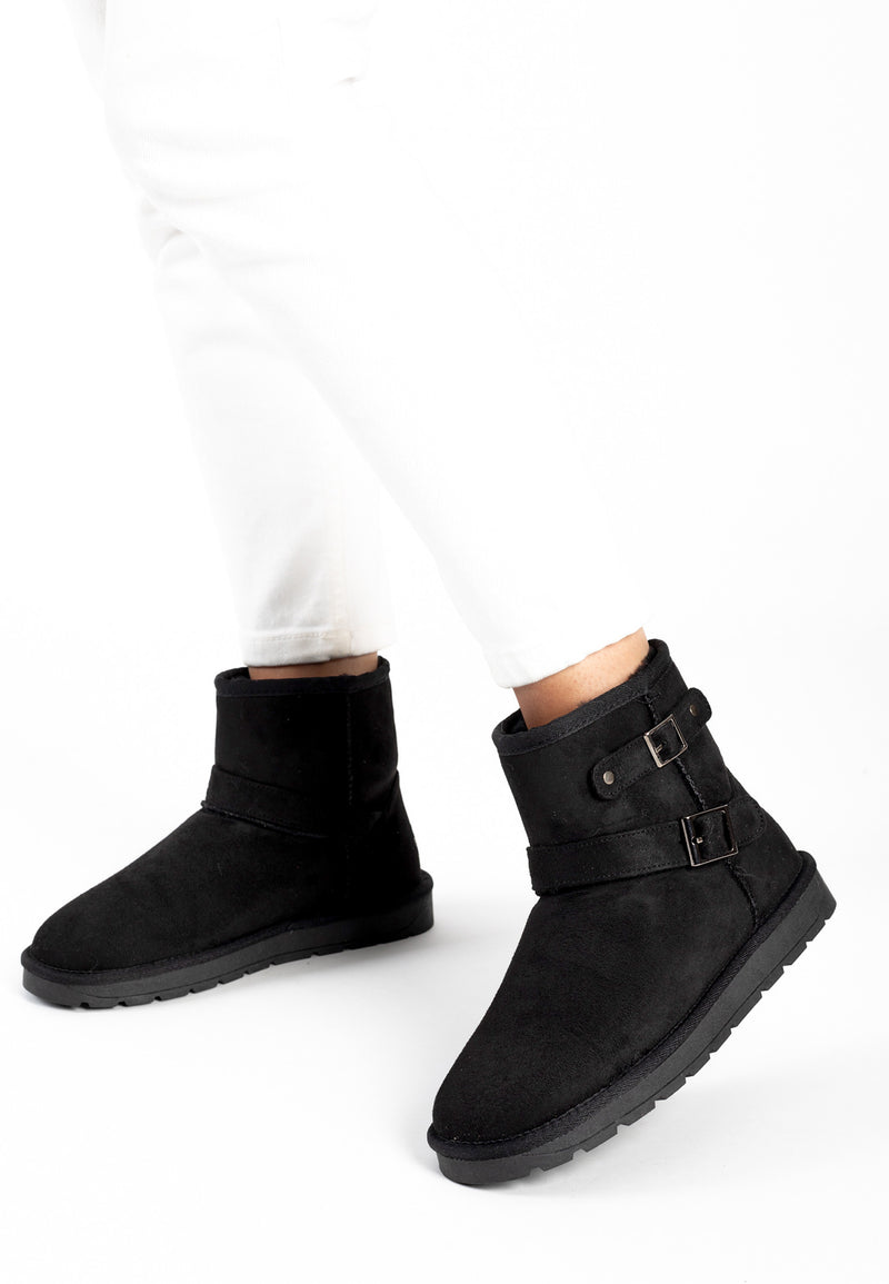 Bottines fourrées Olwen noires portées en marche sous un pantalon blanc droit