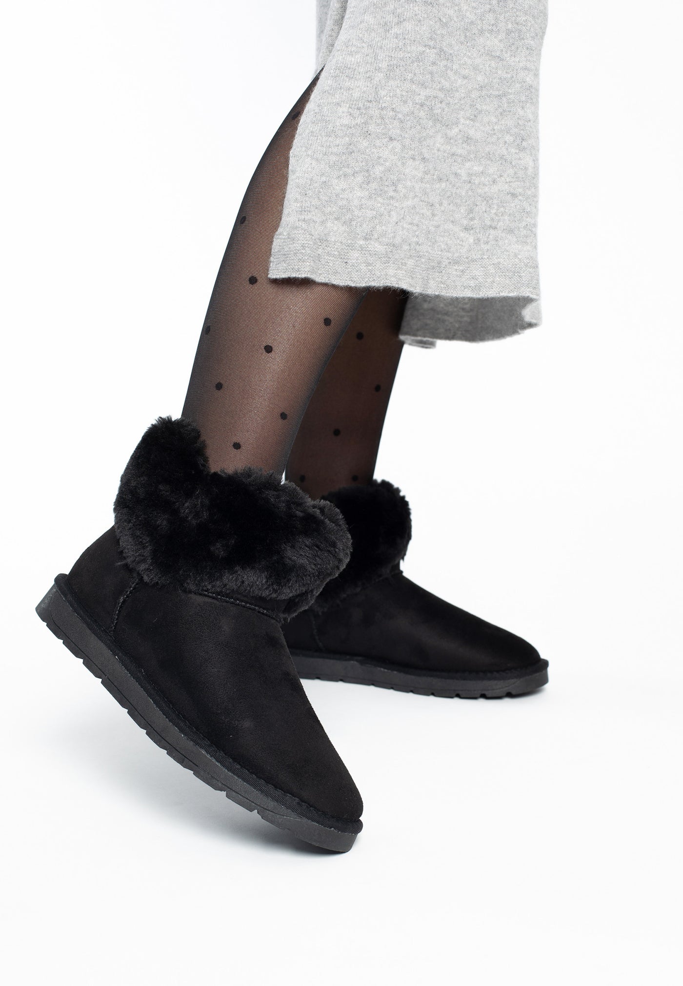 Bottines fourrées Olivia noires portées avec une jupe grise et des collants à pois
