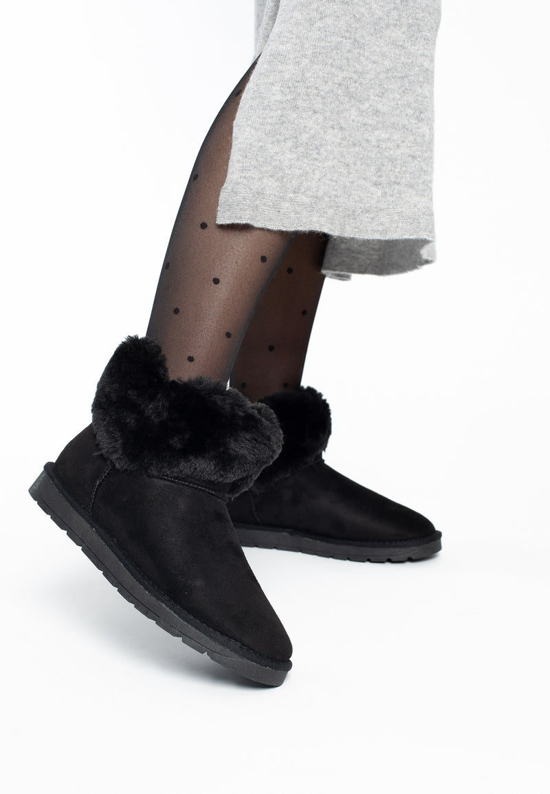 Bottines fourrées Olivia noires portées avec une jupe grise et des collants à pois