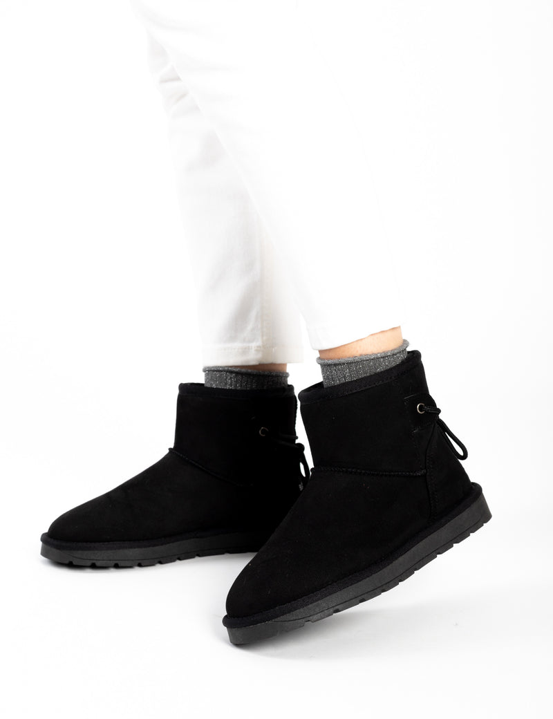 Bottines fourrées Ellaria noires portées avec un pantalon blanc et des chaussettes grises