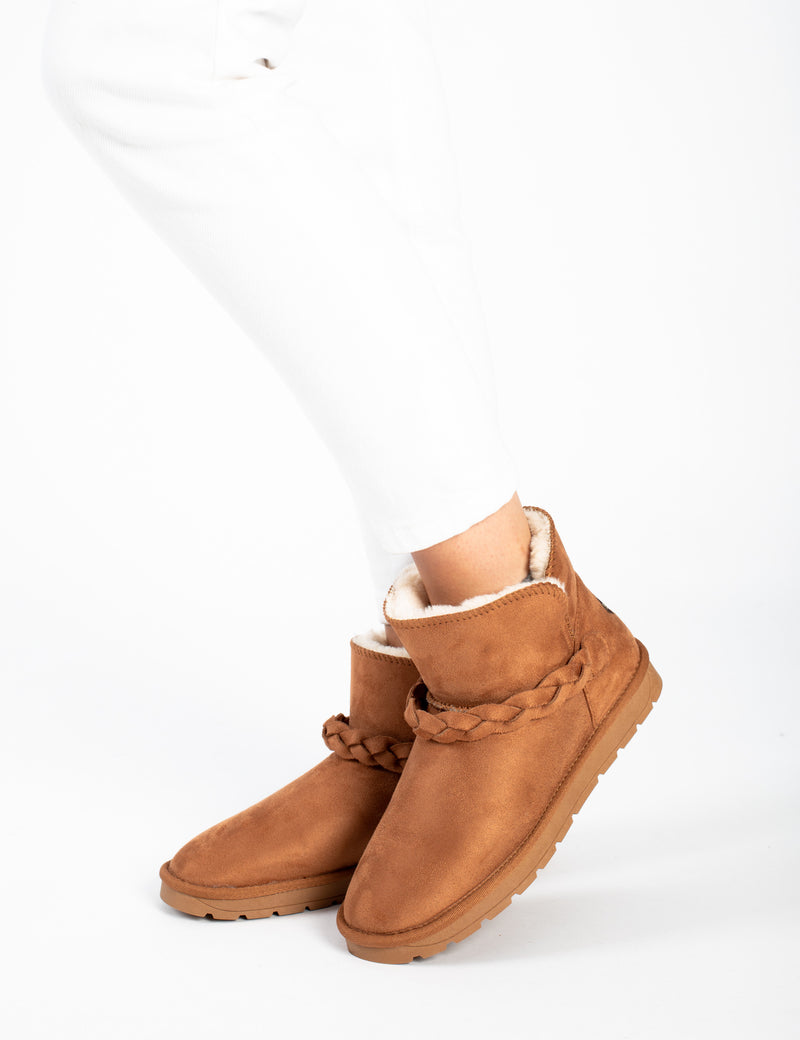 Bottines fourrées Cara camel portées sous un pantalon blanc, tresse visible sur la tige