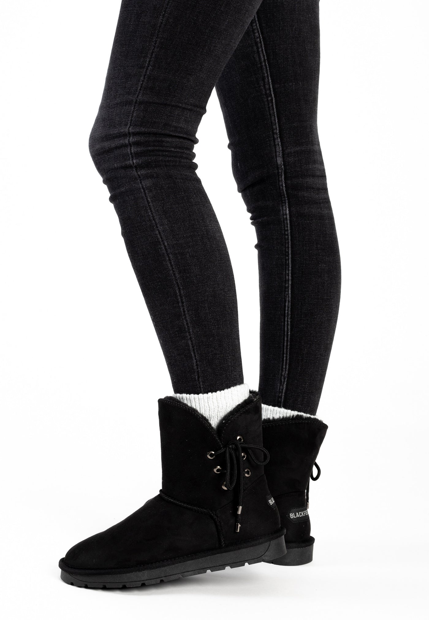 Bottines fourrées Asha noires portées sur un jean noir, chaussettes blanches côtelées