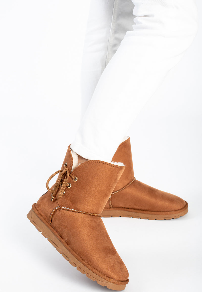 Bottines fourrées Asha camel portées sous un jean blanc, col crème replié au bord