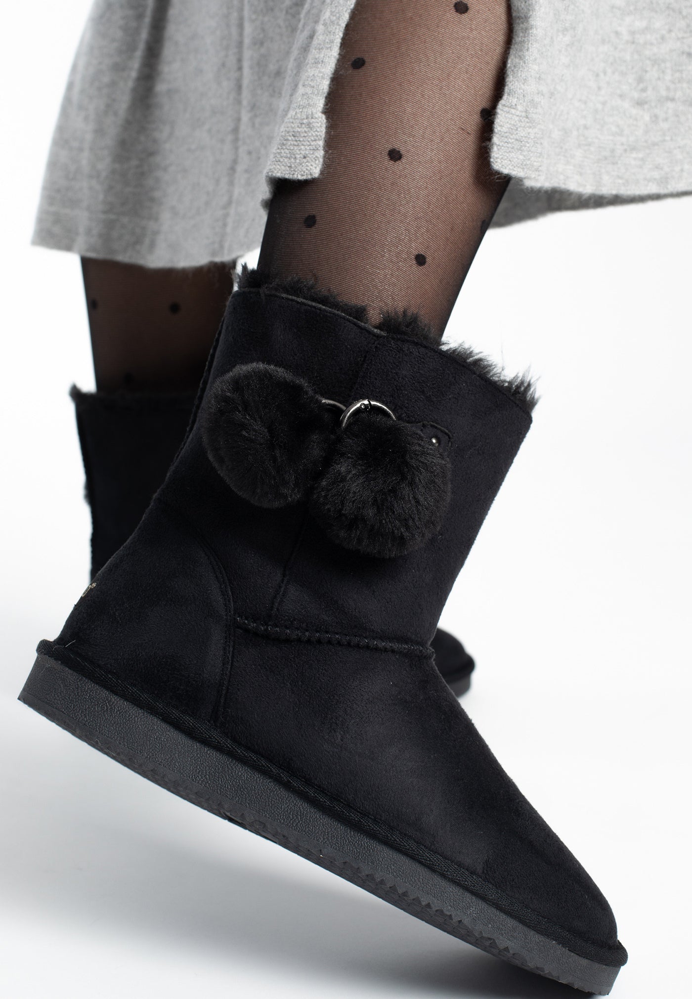 Bottines fourrées Melville noires portées avec un collant à pois et une jupe grise