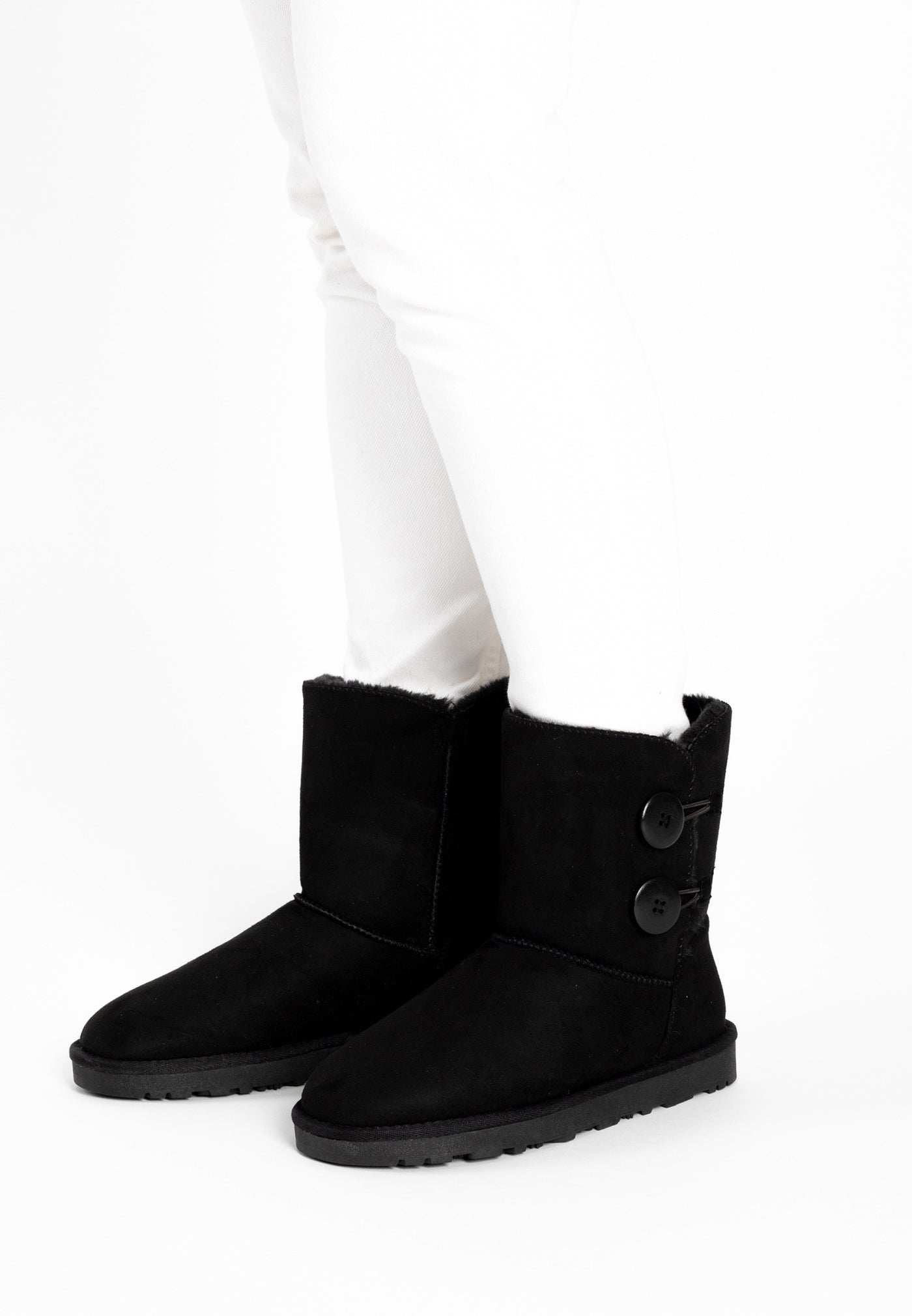 Paire de bottines fourrées Lola noires portées de profil avec un jean blanc droit