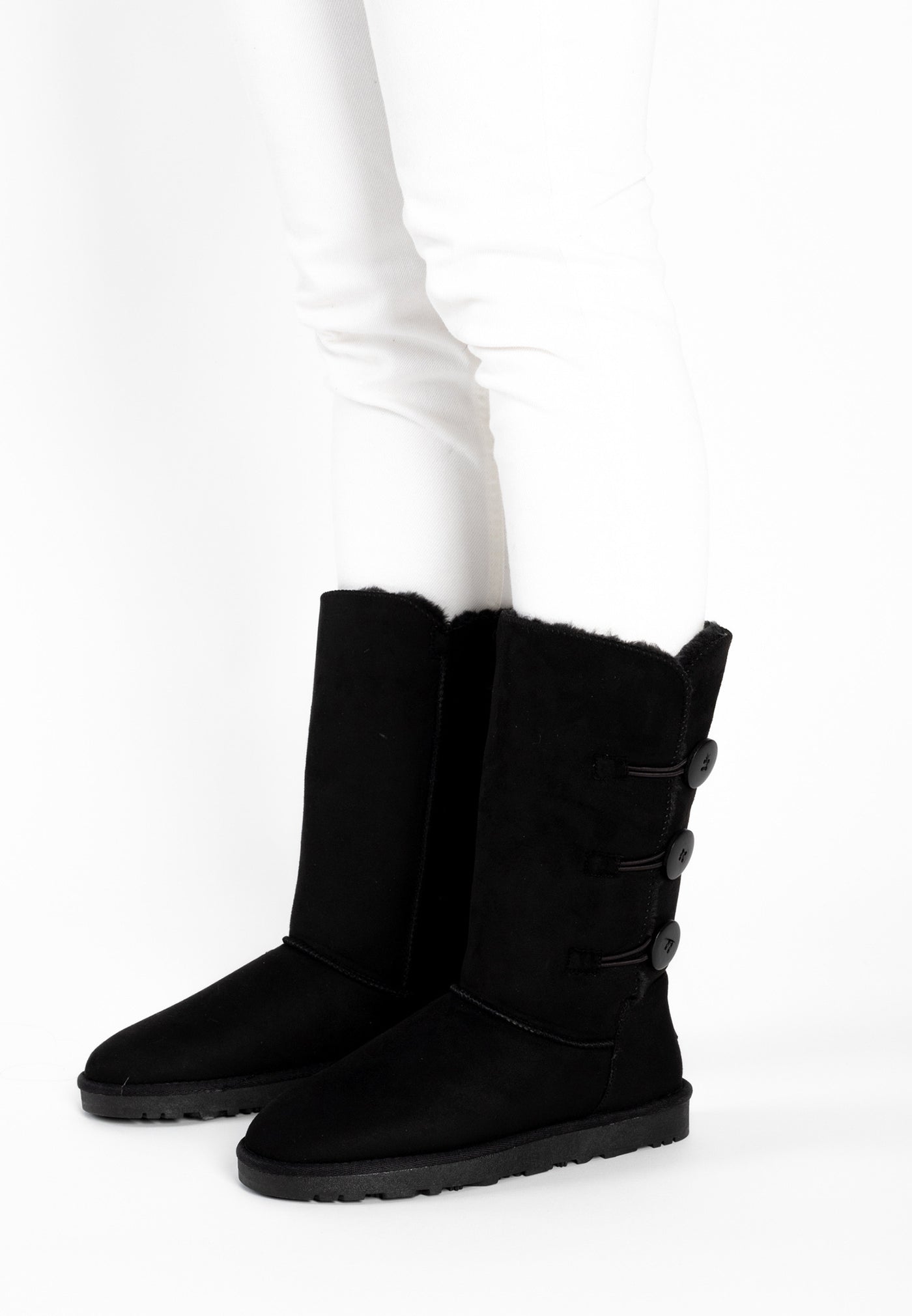 Bottes fourrées hautes Flocon noires portées sur un pantalon blanc, trois boutons alignés
