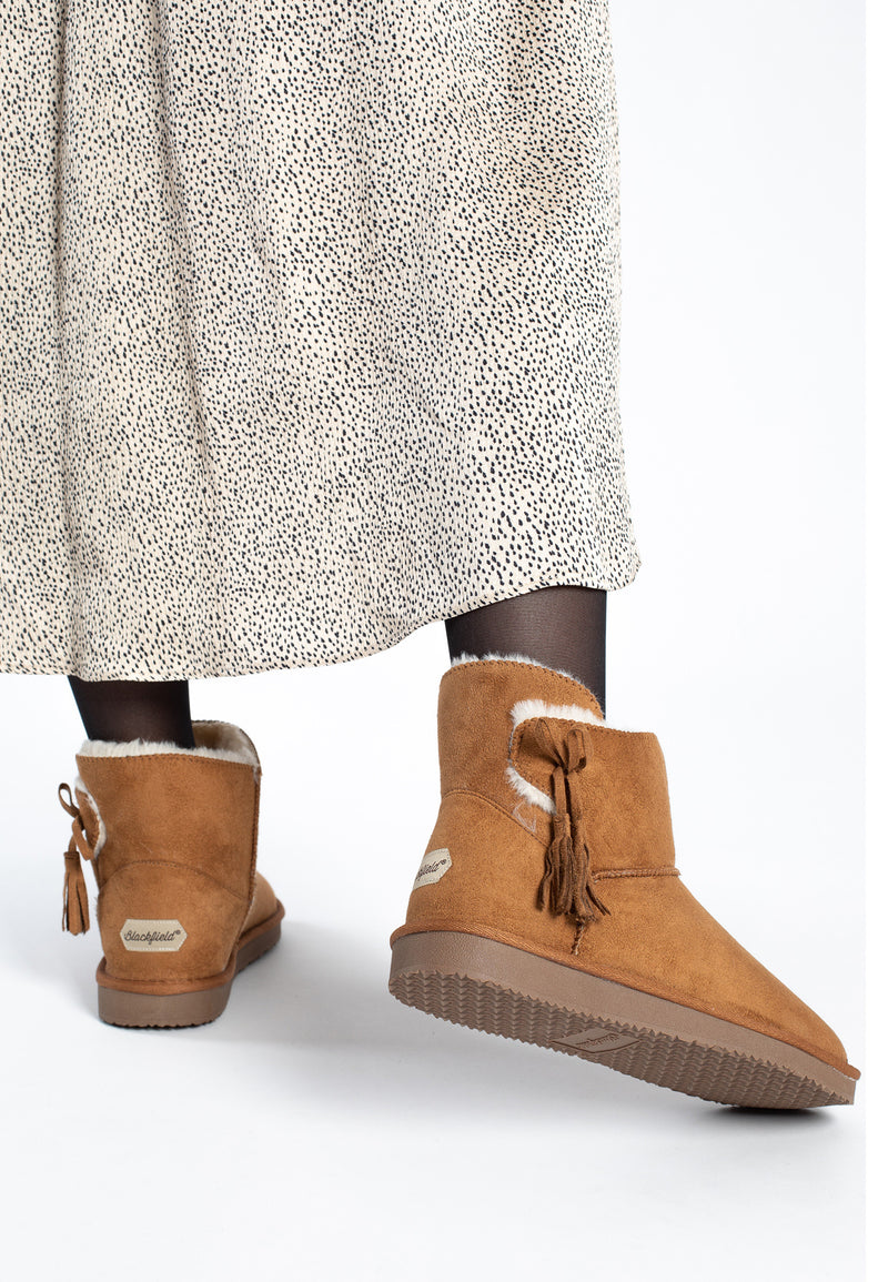 Bottines fourrées Curry camel portées de dos sous une robe longue imprimée