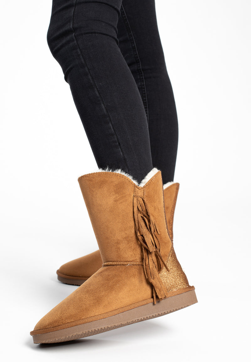 Bottines fourrées Cardero camel portées avec un jean noir, franges en mouvement à la marche
