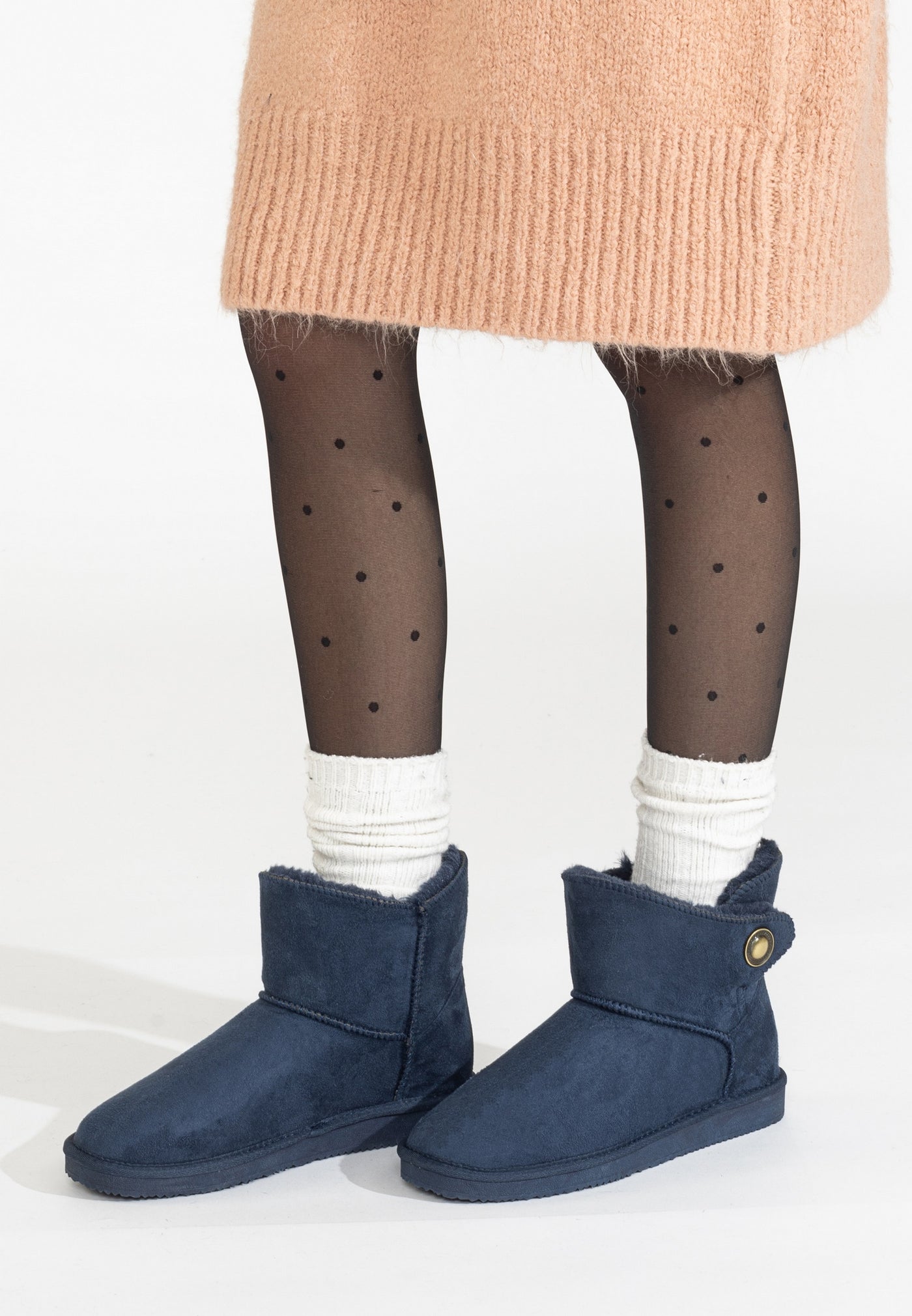 Bottines fourrées Cayuga marine portées avec des collants à pois et une jupe pêche