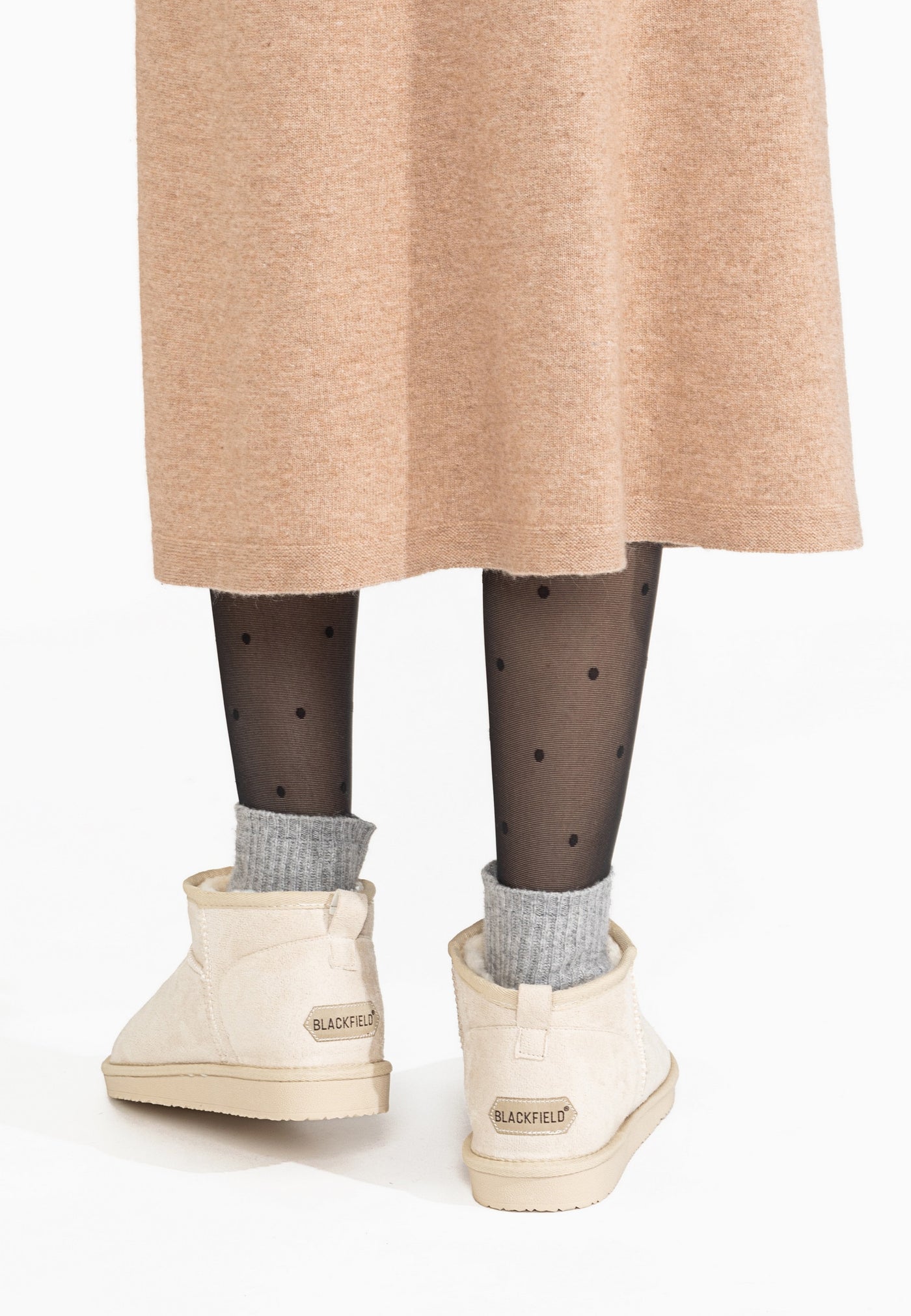 Bottines fourrées Milli écru portées de dos, chaussettes grises repliées sur la tige