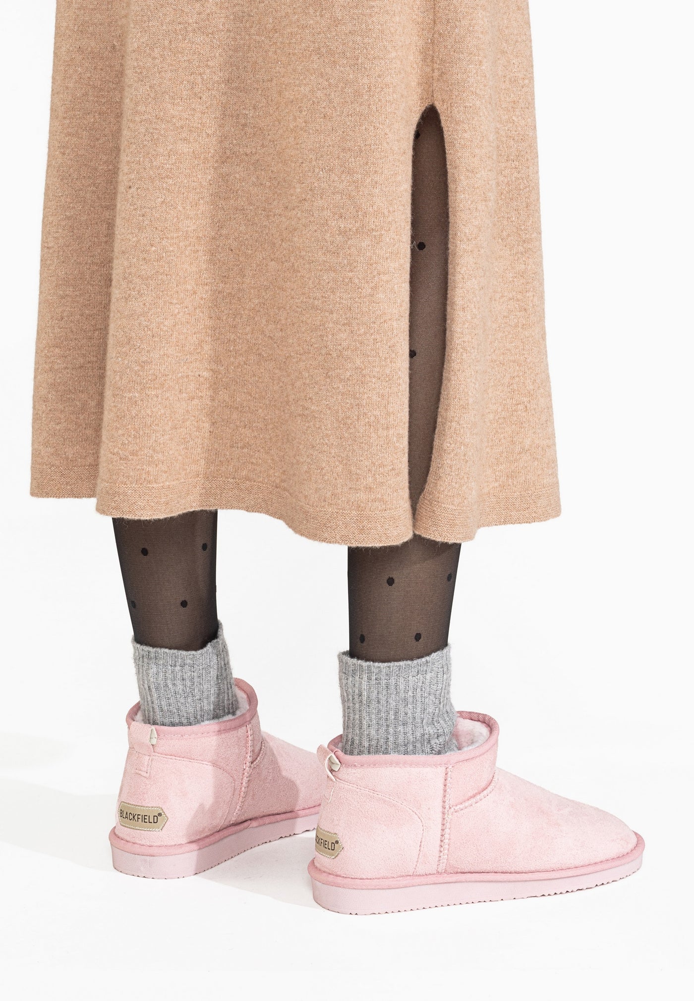 Talons des bottines fourrées Mini Milli roses vus de dos sous une jupe et des chaussettes