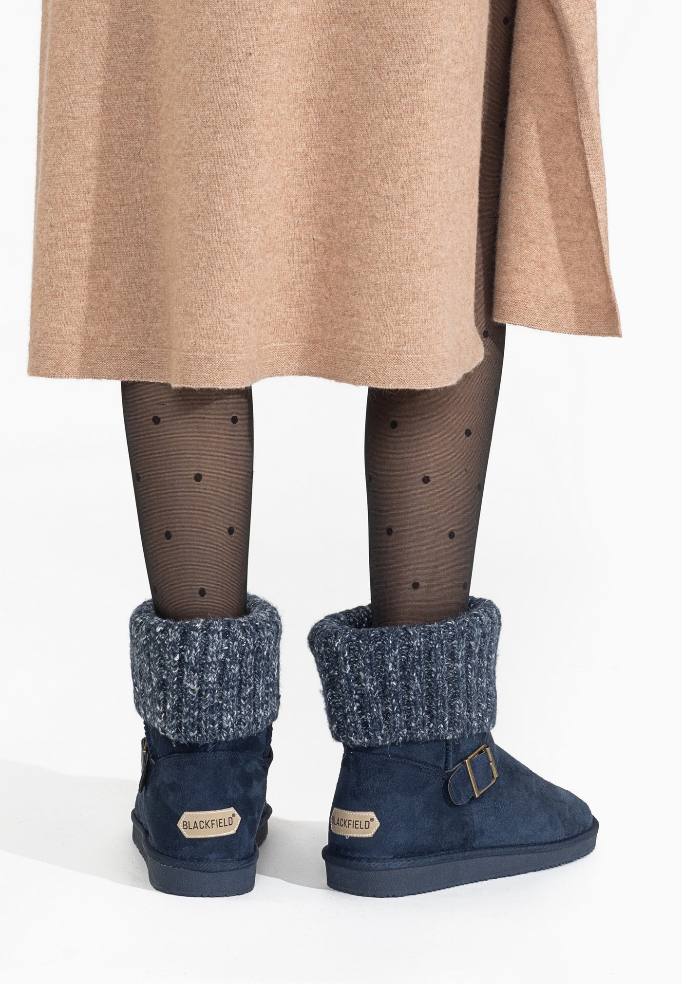 Bottines fourrées Kylie marine portées de dos sous une jupe camel, talons étiquetés