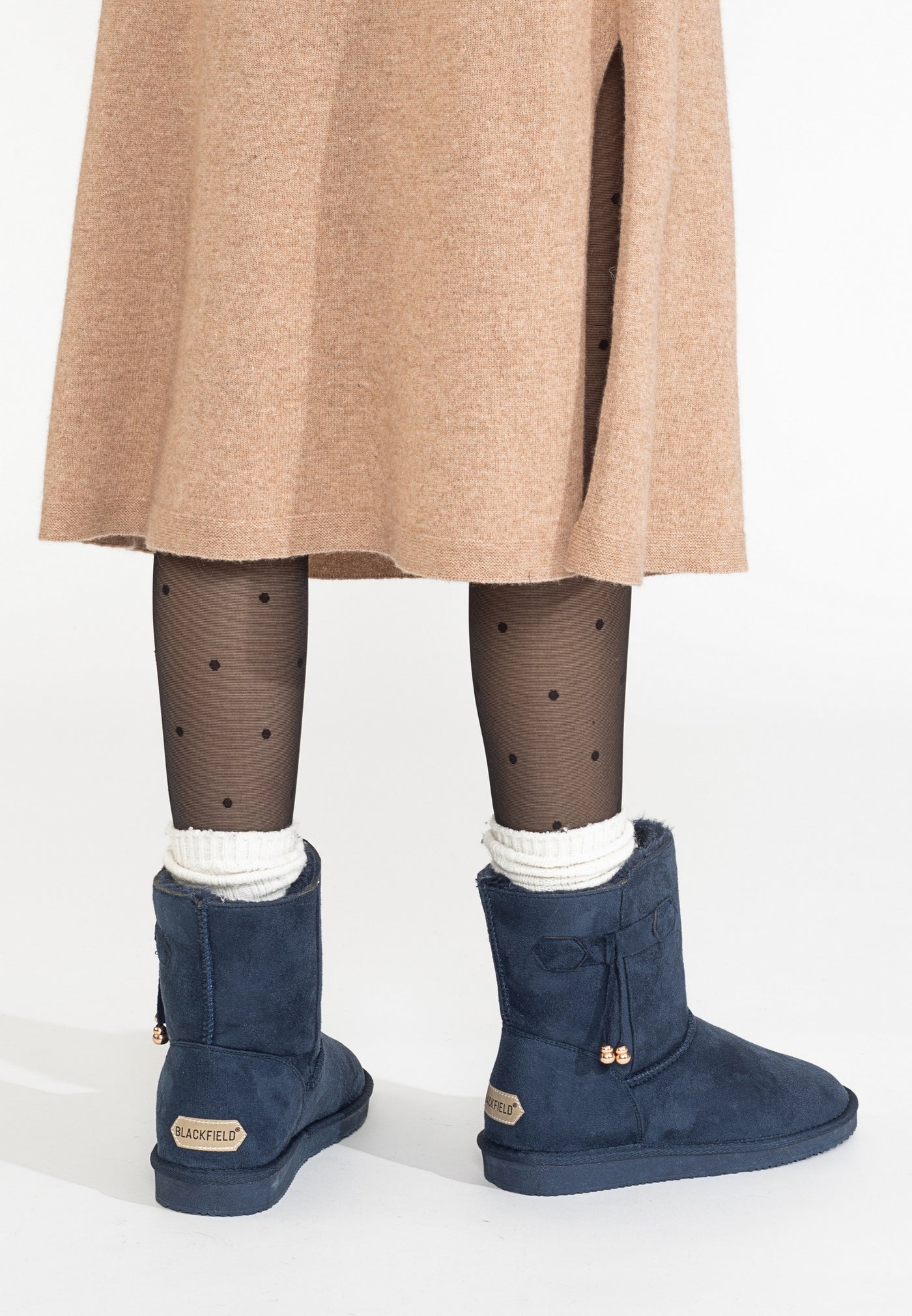 Vue de dos, bottines fourrées Opinaca marine portées avec chaussettes blanches et jupe camel