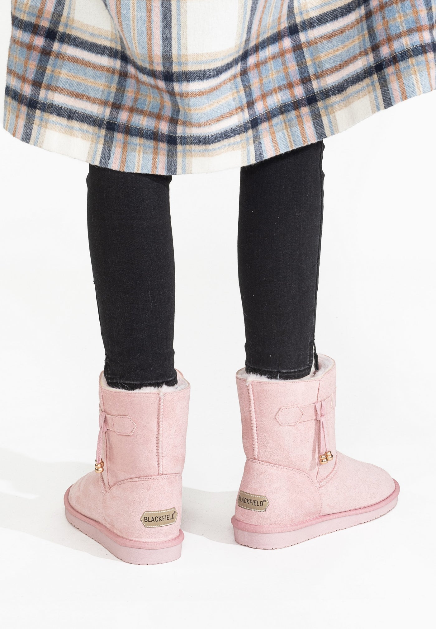 Bottines fourrées Opinaca rose portées de dos, jean noir et manteau à carreaux