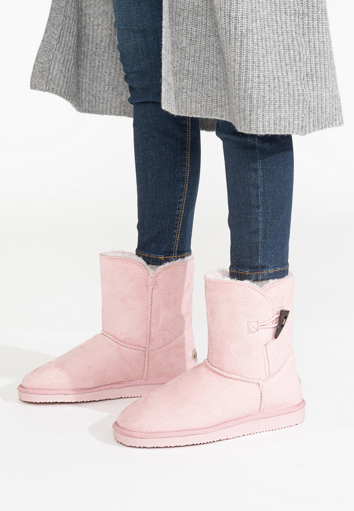 Bottines fourrées Anais rose portées avec un jean brut et un long manteau gris