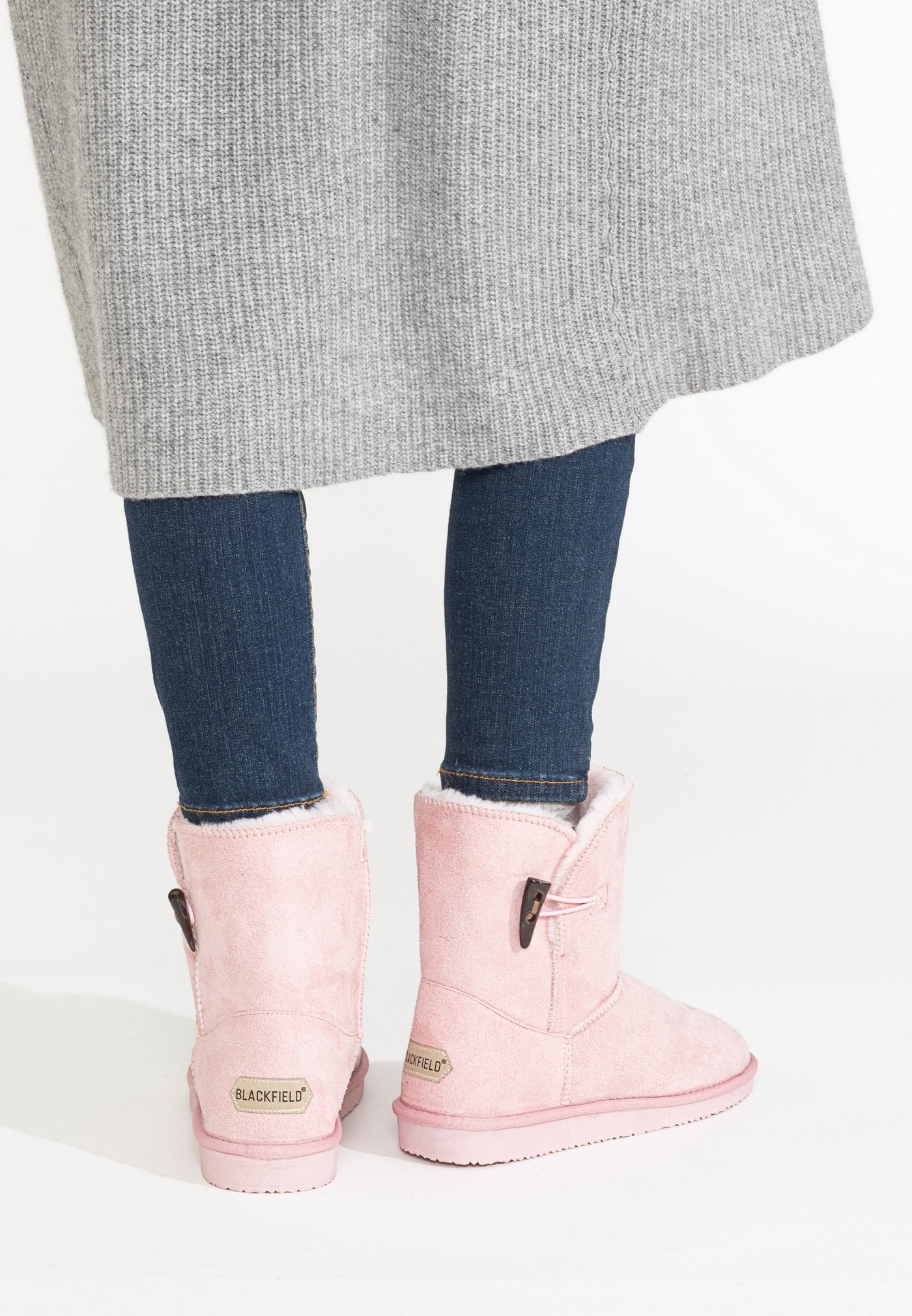 Bottines fourrées Anais rose portées de dos, jean foncé et manteau gris en maille