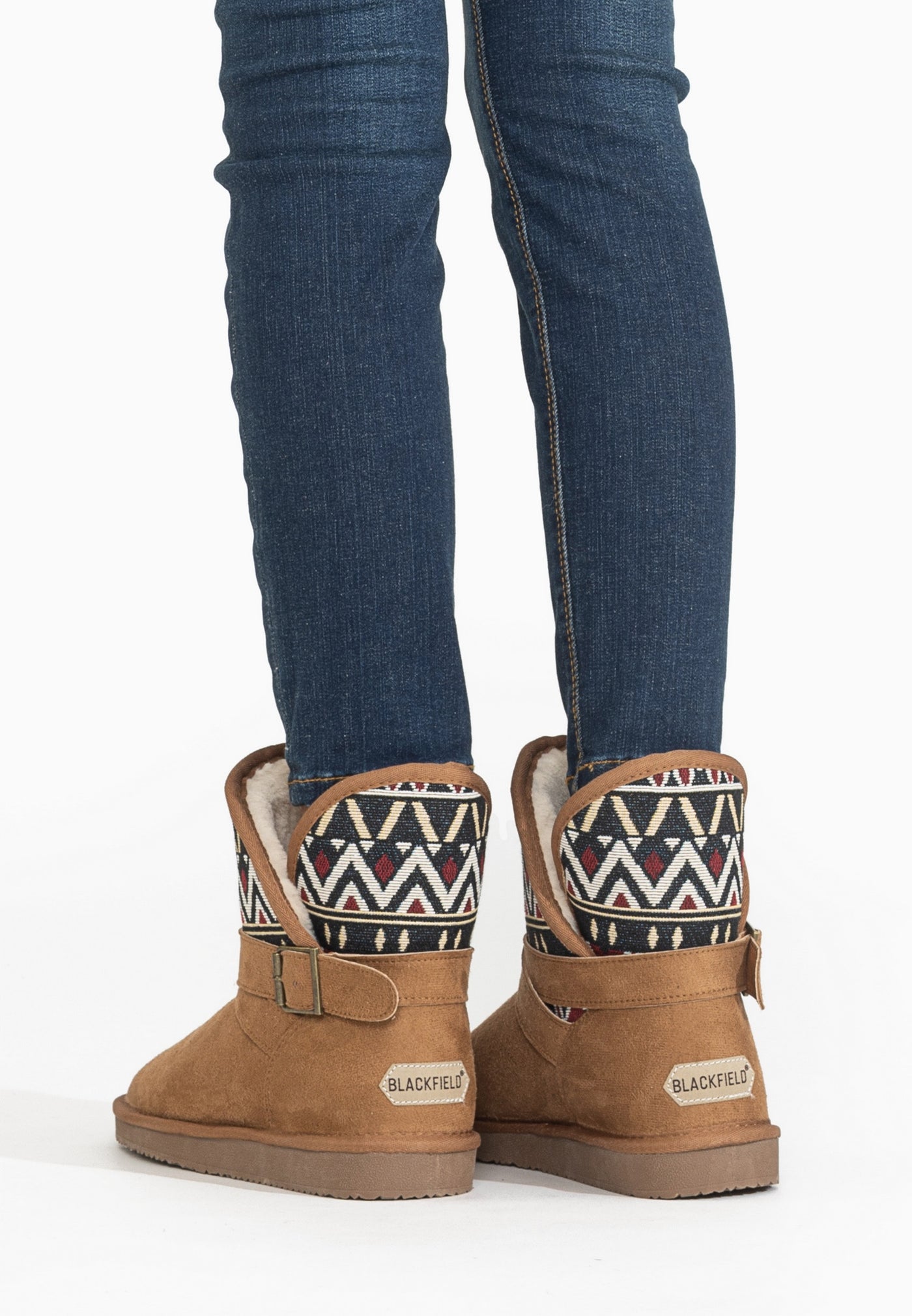 Bottines fourrées Concha camel portées de dos sur un jean skinny, talons alignés