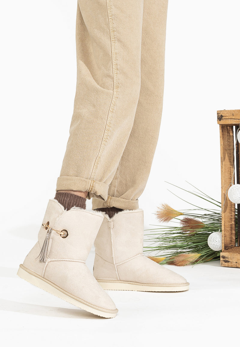 Bottines fourrées Clair naturel portées avec un pantalon beige, décor de branchages