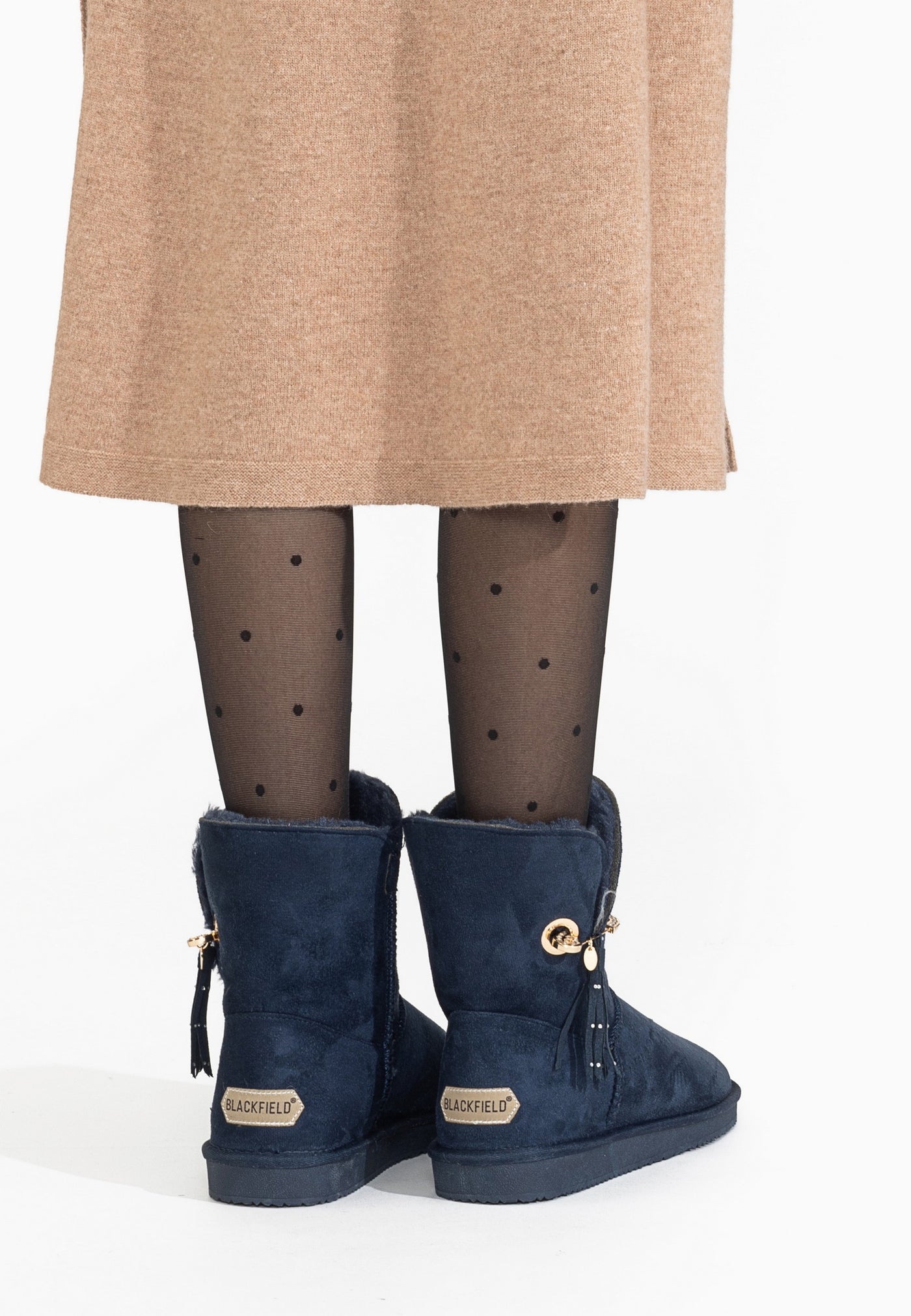 Bottines fourrées Clair marine portées de dos, pompons pendant le long des tiges