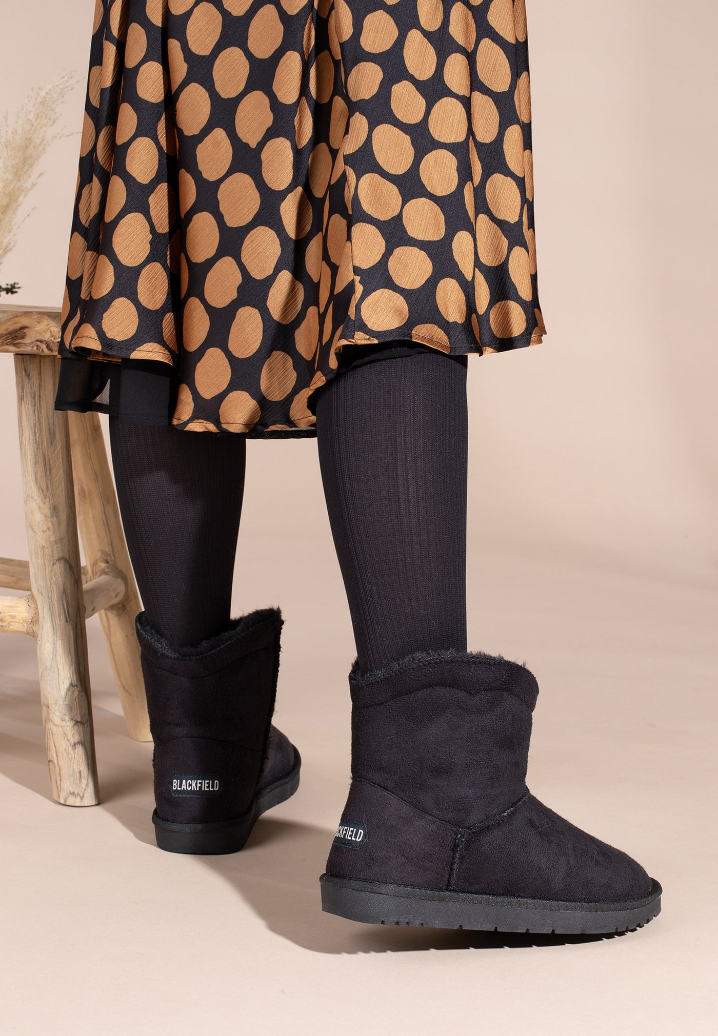 Bottines fourrées Watson noires portées avec un collant côtelé et une jupe à pois
