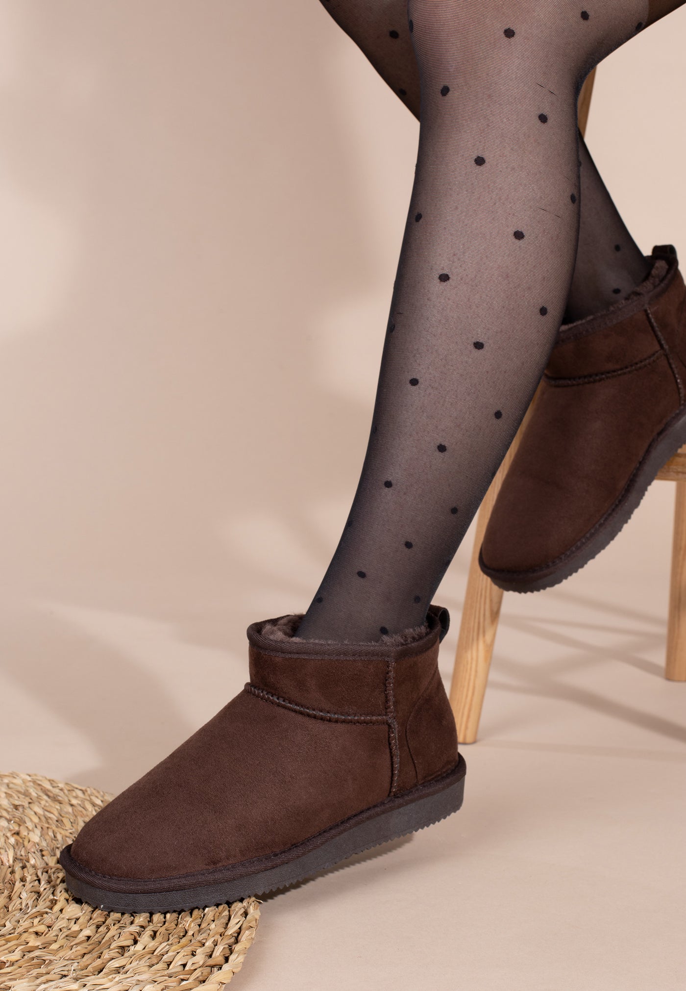 Bottine fourrée Mini Milli marron portée de profil près d'un tapis tressé et de collants