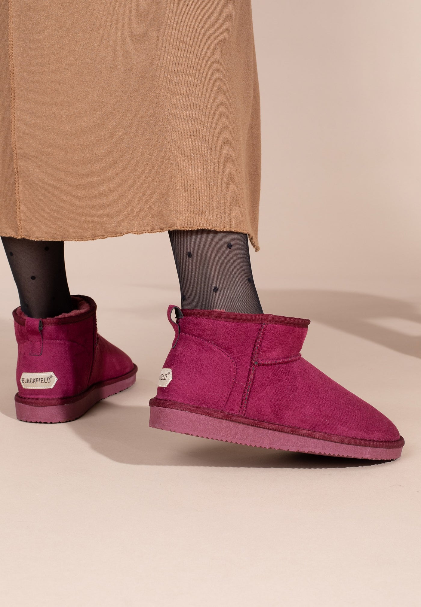 Bottines fourrées Mini Milli bordeaux vues de dos sous une jupe terracotta, étiquette au talon