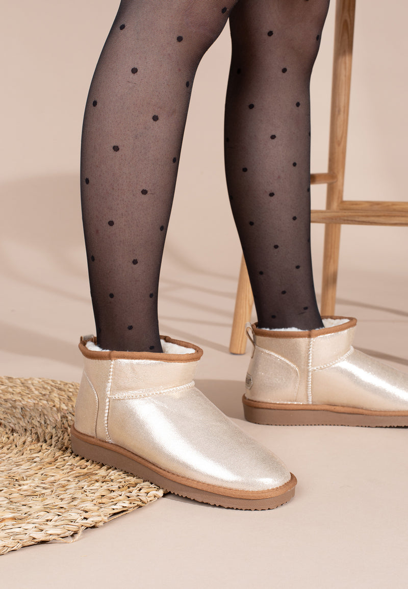 Paire de bottines fourrées Mini Milli beige doré portée près d'un tapis tressé et d'une échelle