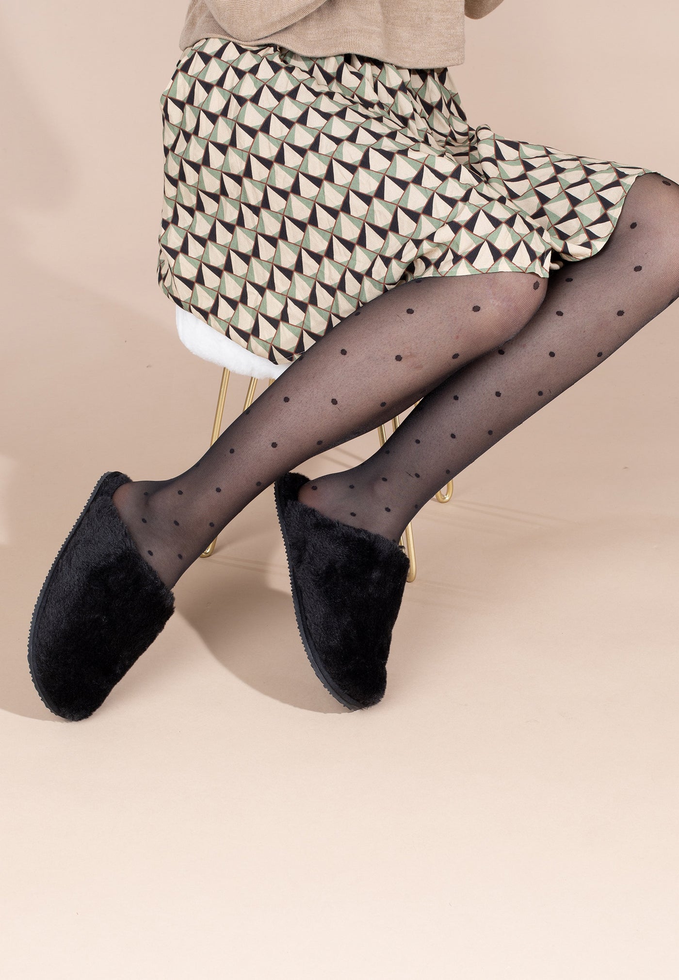 Chaussons fourrés Fraya noir portés avec un collant à pois et une robe imprimée