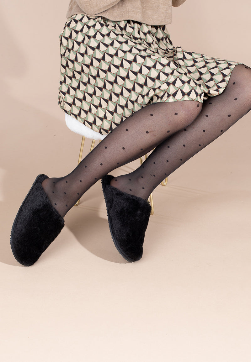 Chaussons fourrés Fraya noir portés avec un collant à pois et une robe imprimée