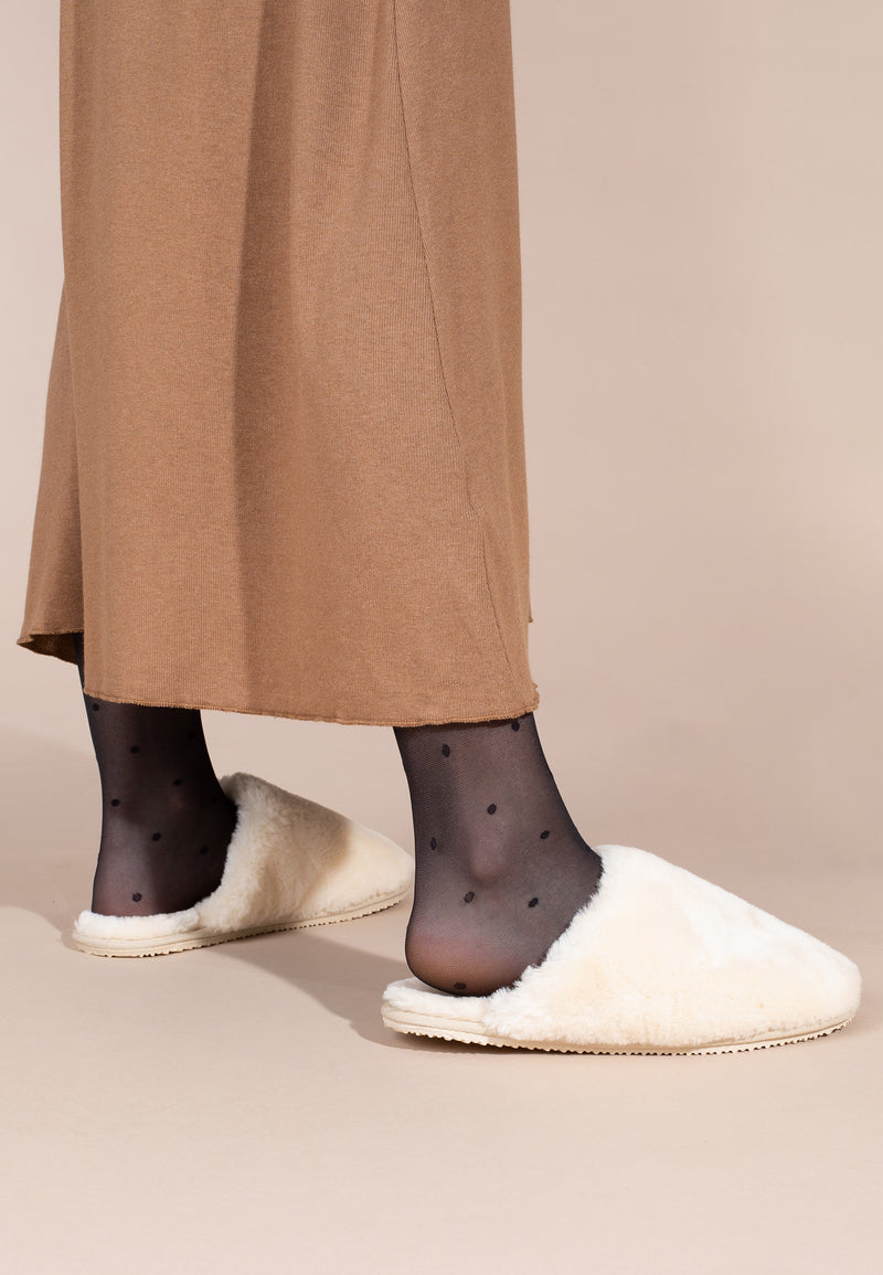 Chaussons fourrés Fraya naturel portés avec un collant sombre et une jupe longue camel