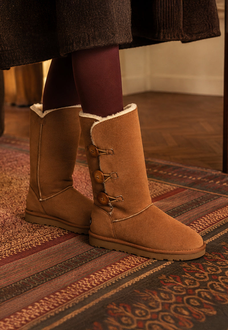 Bottes fourrées hautes Flocon camel portées sur un parquet, avec des collants bordeaux