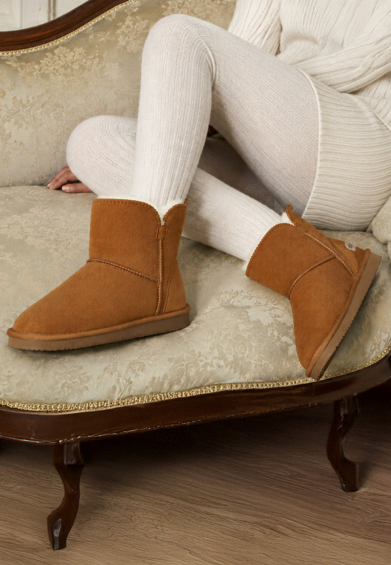 Bottines fourrées Bellevue camel portées avec des collants écrus sur un canapé ancien